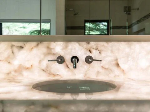 Experience the elegance of a modern bathroom sink with a marble countertop and wall-mounted faucet, meticulously crafted by Studio 250 Design.